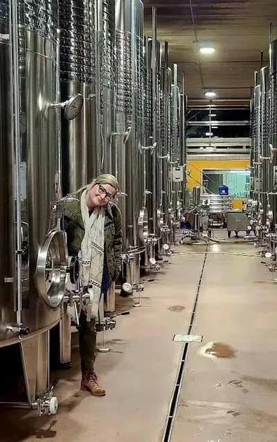 Emily Kuehn of Vino Veritas among stainless wine tanks in a cellar